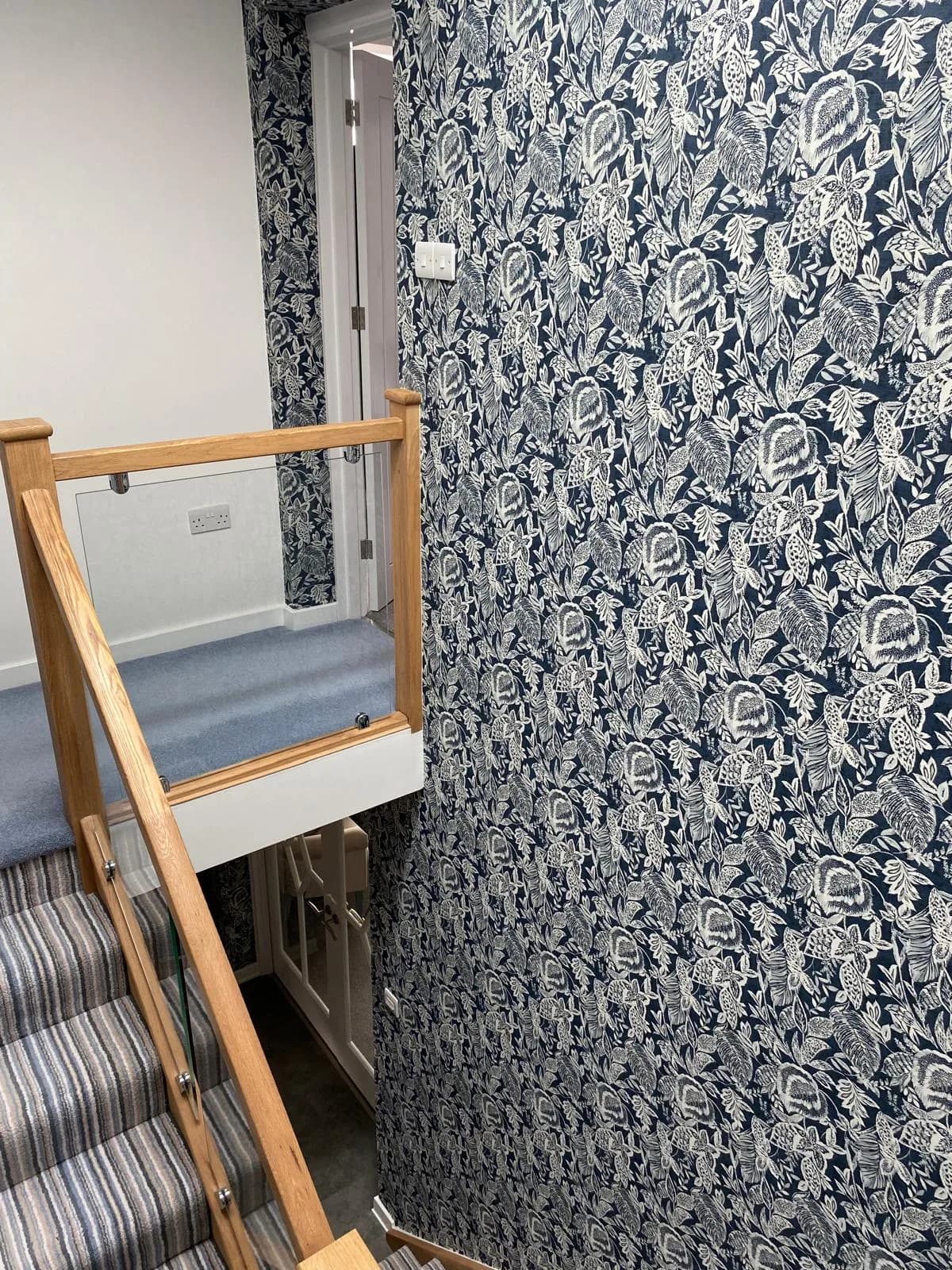 Navy floral wallpaper hung down a stairwell